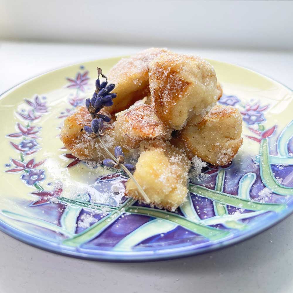 a decorative plate with a lavender design, with five lavender sugar bites and a sprig of lavender